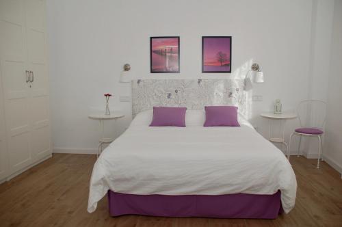 a bedroom with a large white bed with purple pillows at Casa los Tres Nogales in Castroserna de Arriba