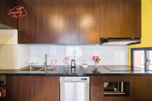 a kitchen with wooden cabinets and a sink and a dishwasher at Dreamy Sky - Airport View Boutique Hotel in Da Nang