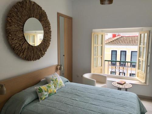 sypialnia z łóżkiem, lustrem i oknem w obiekcie NATURA SUITE MÁLAGA w Maladze