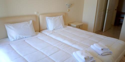 a large white bed with two towels on it at Gorgones, sea-front, great view in Kardamili