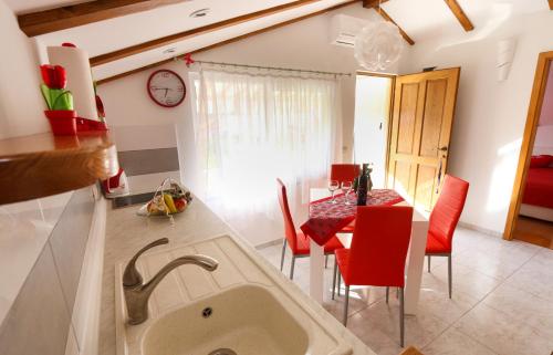a kitchen with a sink and a table with red chairs at Apartmani Pavla in Orebić