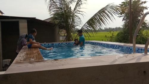 a group of people standing around a swimming pool at Kurau Inn Farmstay in Kuala Kurau