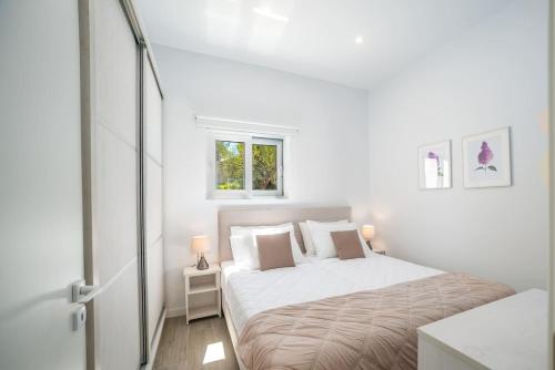 a white bedroom with a bed and a window at CasAlma I in Plános