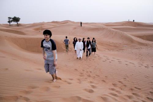a group of people walking through the desert at Bidiya Desert Camp in Aflāj