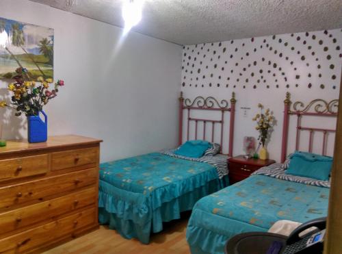 a bedroom with two twin beds and a dresser at Escocie - Centro Historico in Quito