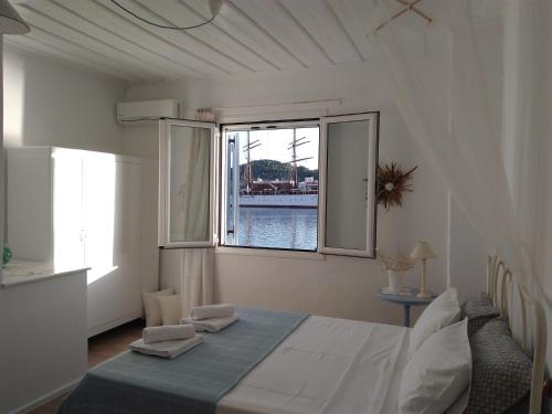 a bedroom with a bed and a large window at Cavos Seaside House in Vathi, Ithaka
