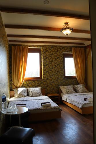 a bedroom with two beds and a table and two windows at Pozingė Pegasas Pokylių namai in Klaipėda