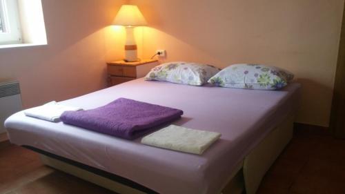 a bed with two pillows and purple towels on it at Apartment Dante in Tisno