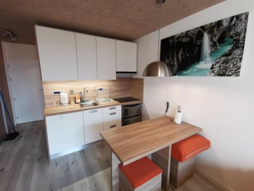 uma cozinha com armários brancos e uma mesa de madeira em Studio Apartment Jež em Bovec