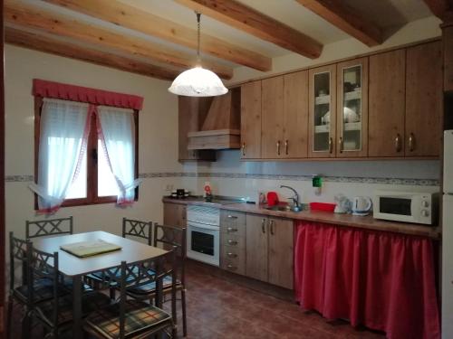 a kitchen with wooden cabinets and a table with chairs at Las Casonas de Chavida in Chavida