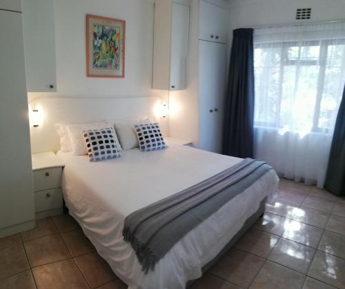 a bedroom with a large white bed with blue pillows at Coons Cove in Cape Town