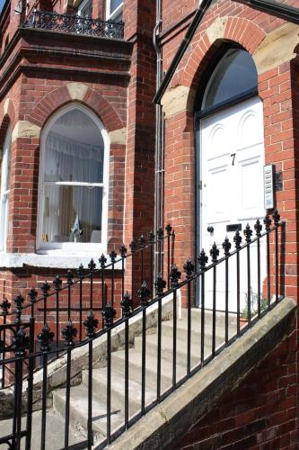 a black fence in front of a brick building with a white door at No3 By The Sea Apartment in Whitby