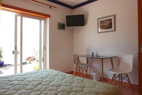 a bedroom with a bed and a table and a television at Tir Na Nog in Alfeizerão