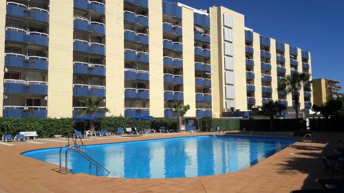 a swimming pool in front of a large building at Apartamentos TSS Alboran in Salou