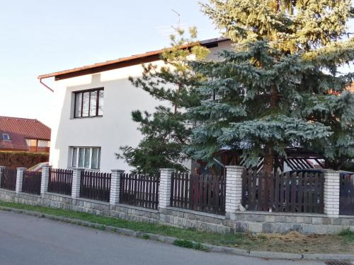 a white house with a fence and a tree at Apartmán Hugo in Kamenný Újezd