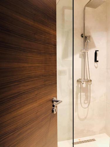 a shower with a wooden door in a bathroom at Boulevard Exclusive in Pristina
