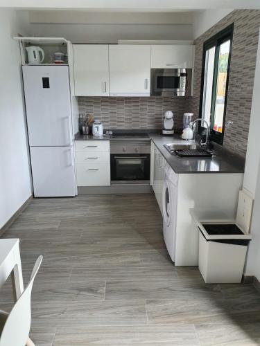 a kitchen with white cabinets and a white refrigerator at luxury casa playa roca bord de mer in Costa Teguise