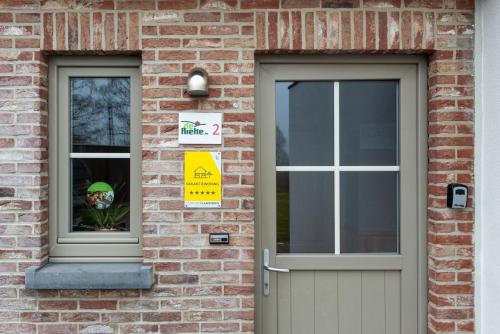 a door to a brick building with a sign in the window at De Rieke in Ronse