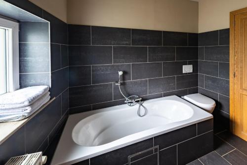 a bathroom with a large tub and a toilet at De Rieke in Ronse
