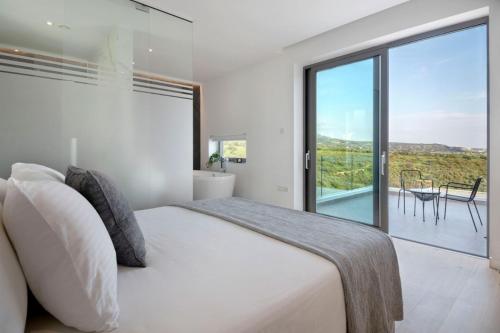 a white bedroom with a large bed and a balcony at Elea Silver Villa in Peyia