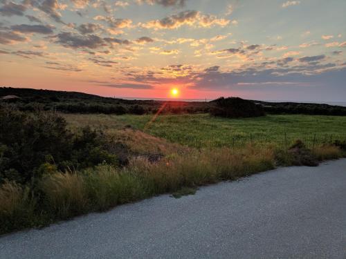 a sunset over a field with a road and grass at White Lake Holiday House in Elafonisi