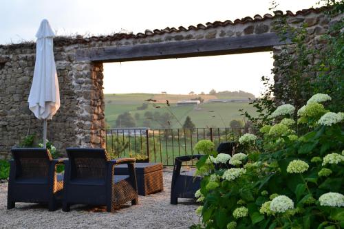 a patio with chairs and an umbrella and flowers at La Paresse en Douce in Tours-sur-Meymont