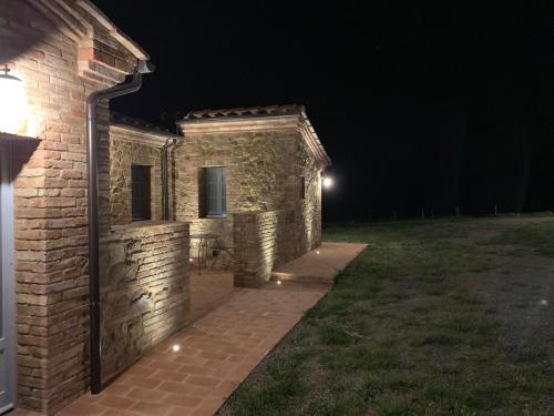 un edificio de ladrillo por la noche con una luz encendida en Cordella In Valdorcia Truffle and Olive Oil Resort, en Montalcino