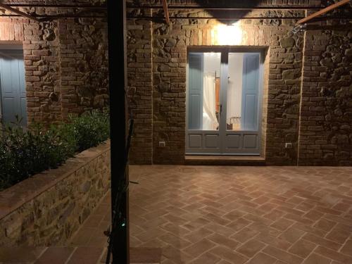 een voordeur van een gebouw met een bakstenen muur bij Cordella In Valdorcia Truffle and Olive Oil Resort in Montalcino