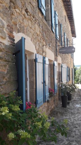a building with blue doors and flowers on a street at La Paresse en Douce in Tours-sur-Meymont