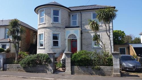 a gray brick house with a red door at Grantham House in Ryde