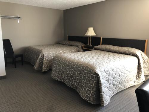 A bed or beds in a room at Arbour Ridge Inn & Suites