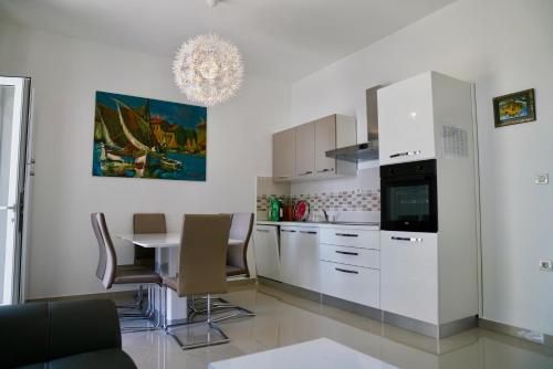 a kitchen with white cabinets and a table with chairs at Sesar Apartments Krk - No. 1 Iva in Krk