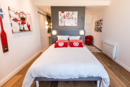 a bedroom with a large white bed with red pillows at Le Clos de la Pointe Saint-Mathieu in Plougonvelin