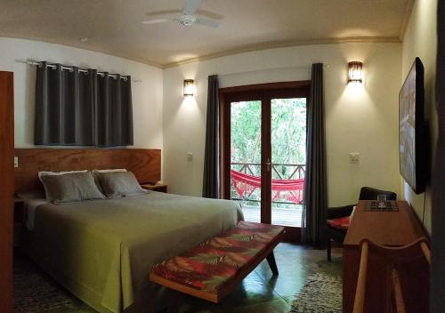 a bedroom with a large bed and a balcony at Pousada Vila Araticum in Santo André