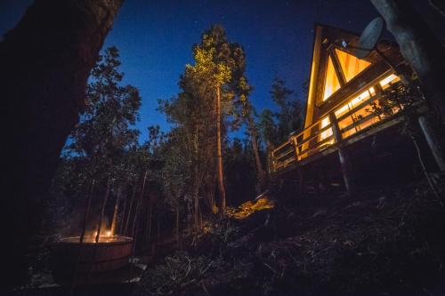 a lit up cabin in the woods at night at Puente Palos San Pedro in Castro