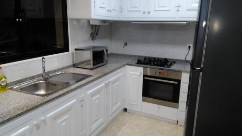a kitchen with white cabinets and a sink and a microwave at Vista Atlântico in Gaula