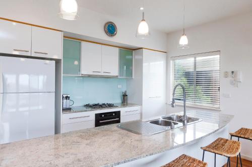 a kitchen with white cabinets and a sink at Bella vista in Maslin Beach