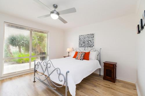 a white bedroom with a bed and a window at Bella vista in Maslin Beach