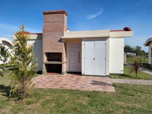 a white house with a garage and a tree at Cabañas Elabu in San Miguel del Monte