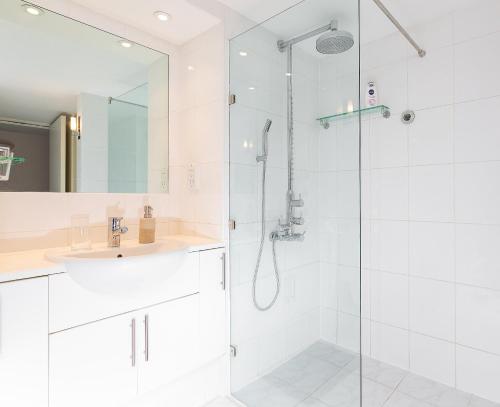 a white bathroom with a shower and a sink at Excellent Apartment with Private PATIO, and PARK across the road in London