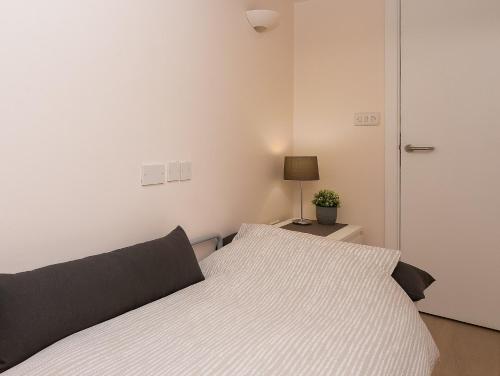 a white bedroom with a bed and a lamp at Excellent Apartment with Private PATIO, and PARK across the road in London