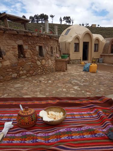 a table with a bowl of food on a blanket at Hostal Qhana Pacha in Isla de la Luna
