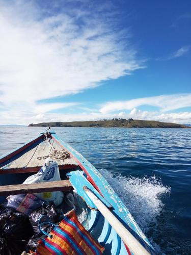 a boat in the water with an island in the background at Hostal Qhana Pacha in Isla de la Luna