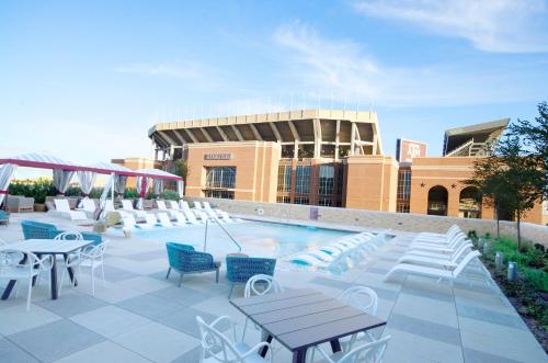 - une piscine avec des chaises et des tables en face d'un bâtiment dans l'établissement Texas A&M Hotel and Conference Center, à College Station