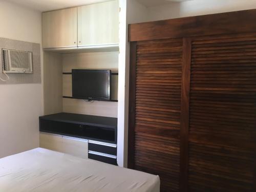 a bedroom with a bed and a television and a closet at Flat a 100m da melhor praia de Alagoas in Praia do Frances