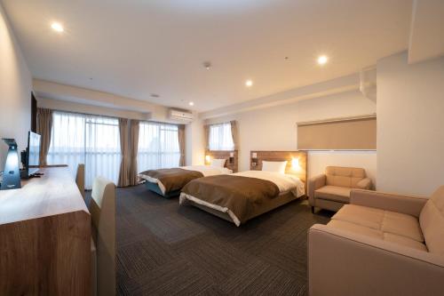和歌山市にあるHOTEL CITY INN WAKAYAMA 和歌山駅前のベッド2台とソファが備わるホテルルームです。