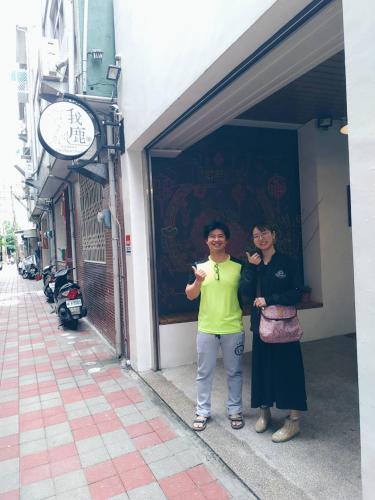 two people are standing outside of a building at mydeer backpacker in Tainan