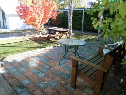 a patio with a table and a picnic table and a bench at Central Chalets Ltd in Alexandra