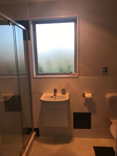 baño con aseo y lavabo y ventana en Broadfield, en Rolleston