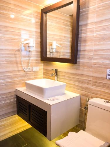 a bathroom with a sink and a mirror and a toilet at The Piccolo Hotel of Boracay in Boracay